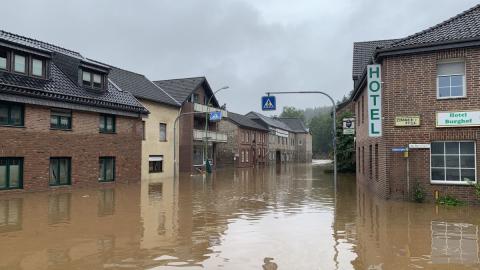 schlammiges Wasser, überflutete zweistöckige Häuser, Verkehrsschild