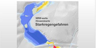 Kartenausschnitt mit grau, blau, gelb und rot eingefärbten Flächen. Text: NRW-weite Hinweiskarte Starkregengefahren